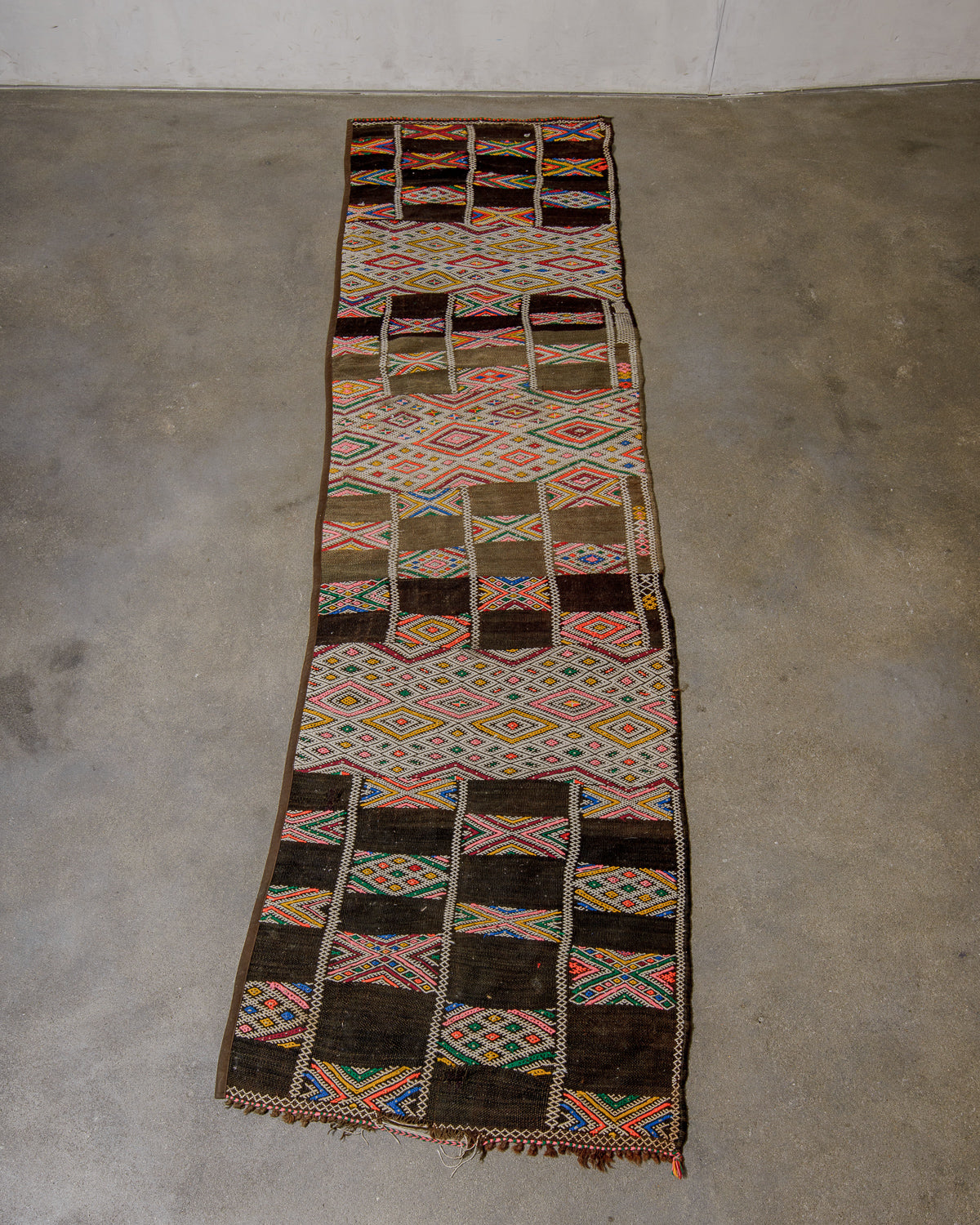 Colourful patterned rug on a concrete floor.